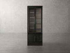 a tall black cabinet with glass doors on the front and bottom shelves, in an empty room