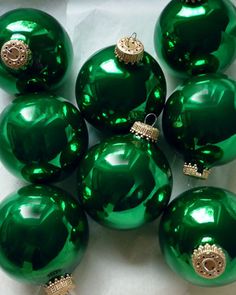 green glass christmas ornaments with gold trimmings on white paper, ready to be used as decorations