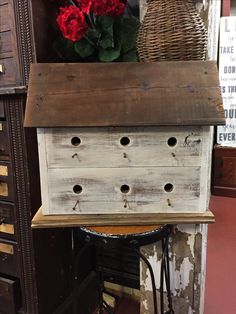 an old dresser with several drawers on it and some flowers in the corner next to it