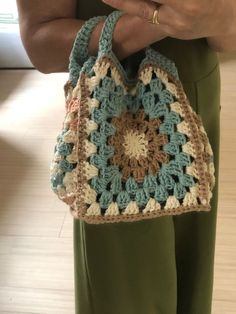 a woman holding a crocheted purse in her hands