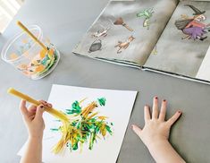 a child's hand is holding a pencil and drawing on paper