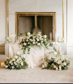 a table topped with lots of white flowers and candles