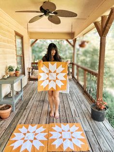 a woman standing on a porch holding an orange and white piece of cloth with stars