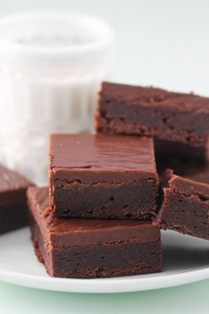 several pieces of chocolate brownies on a plate next to a small cup of yogurt