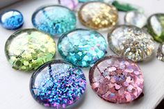 many different colored glitters are arranged on a white surface with small holes in the middle