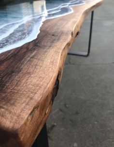 a close up of a wooden bench with water on it's surface and the ocean in the background