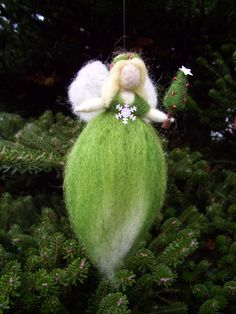 a green ornament with a white angel on it's back hanging from a tree