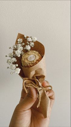 a person holding a small bouquet of flowers in their left hand and wrapped in brown paper