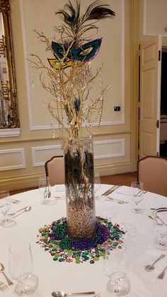 there is a vase with feathers and beads in it on the dining room round table