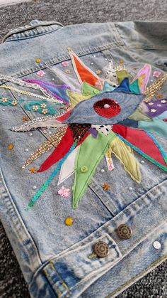 a pair of jeans with colorful patches and buttons on the back of one jean jacket