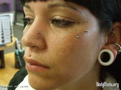 a close up of a person with piercings on their nose and eyelid mirrors in the background