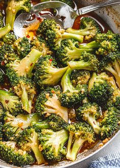 broccoli is being cooked in a skillet with tongs on the side