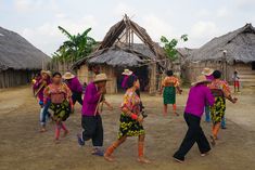 a group of people dancing in front of huts