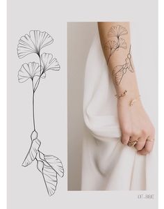 a woman's arm with tattoos on it and a drawing of a flower in the background