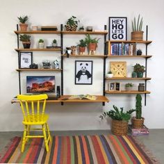 a yellow chair sitting in front of a wooden shelf filled with books and plants on top of it