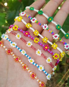 a hand holding several different colored bracelets on it's left wrist, with flowers in the middle