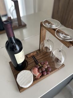 a wine bottle and two glasses on a wooden tray