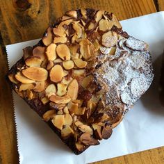 two desserts sitting on top of white paper next to each other, one topped with powdered sugar