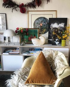 a white chair sitting in front of a shelf filled with pictures and other decor items