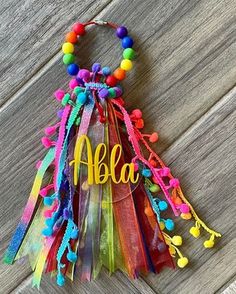 a colorful necklace with the word abla on it and pom poms attached to it