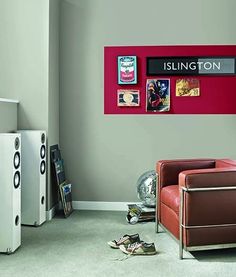 a living room filled with furniture next to a red wall and white speakers on the floor