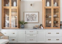 a kitchen with white cabinets and glass doors