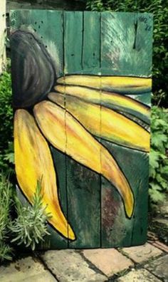 a painted wooden box sitting on top of a brick walkway next to plants and bushes