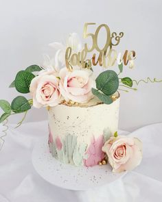 a white cake with pink flowers and greenery on top that says 50 years ago