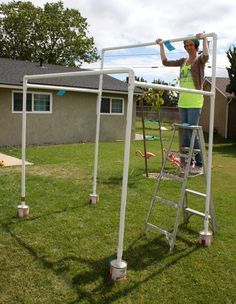 a woman standing on top of a white ladder next to a green field with a blue frisbee