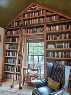 a room with a ladder, chair and bookshelf full of books in it