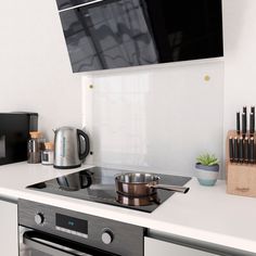 a stove top oven sitting inside of a kitchen under a flat screen tv mounted above it