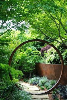 a circular metal sculpture in the middle of a garden