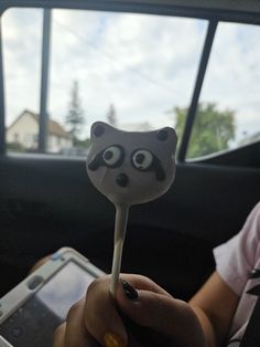 a raccoon shaped lollipop stick in the passenger seat of a car