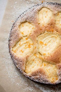 a baked dessert with powdered sugar and orange zest on it's crust