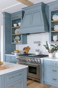 a kitchen with blue cabinets and white counter tops is pictured in this image, there are dishes on the shelves above the stove