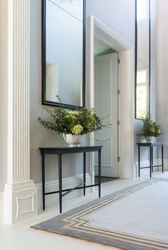 there is a plant in the vase on the table next to the mirror and two chairs