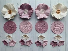 some pink and white paper flowers on a wooden surface with words written in them,