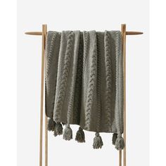 a gray blanket hanging from a wooden rack with two tassels on the top