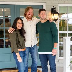 two men and a woman standing in front of a house