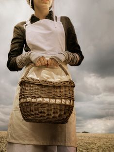 a woman in an apron holding a wicker basket