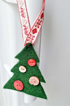 a christmas tree ornament hanging from a white door with red buttons on it