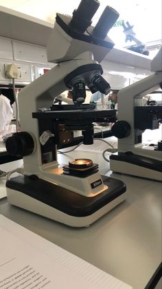 two microscopes sitting on top of a table next to some papers and other items