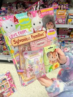 a person holding up a package of toys in front of a store filled with dolls