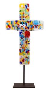 a cross made out of stained glass and painted with different colors on the top, sitting on a black stand