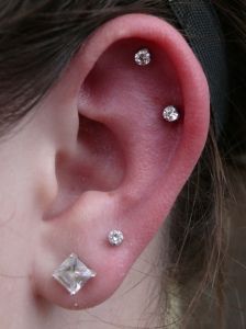 a close up of a person's ear with three diamond studs