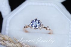 an engagement ring with a blue stone surrounded by three diamond accents on a white cloth