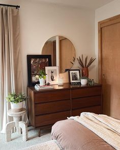 a bedroom with a dresser, mirror and pictures on it