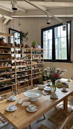 a wooden table topped with white plates and bowls