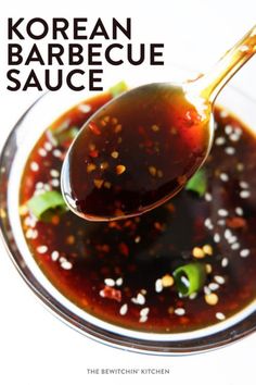 a spoon full of korean barbecue sauce on top of a glass bowl with sesame seeds