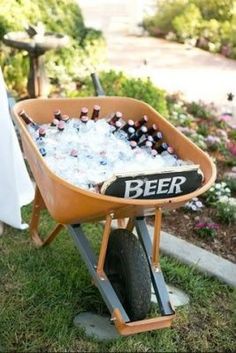 a wheelbarrow filled with beer bottles sitting in the grass